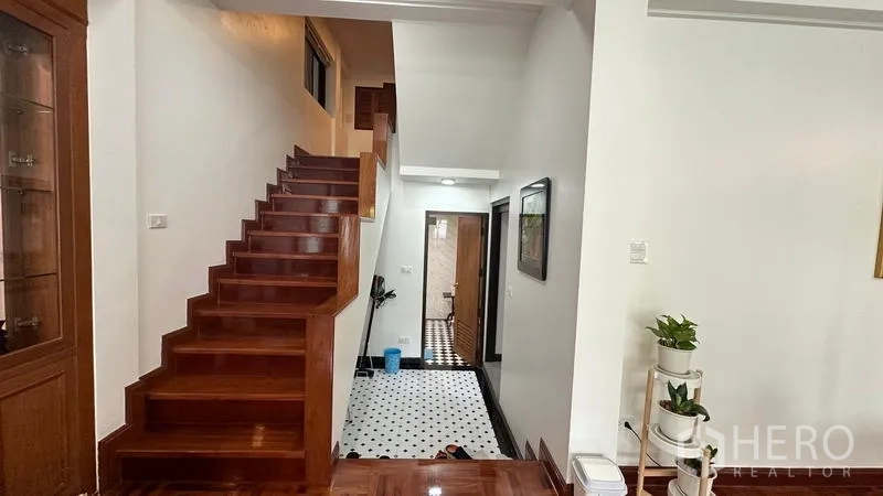 Detached House for rent in Watthana, Bangkok - Stairway from living room to lower corridor with monochrome floor tiles.