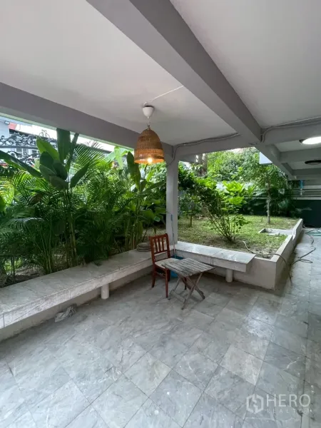 Detached House for rent in Watthana, Bangkok - Ground-floor patio with tiled flooring, built-in benches and raised garden beds.