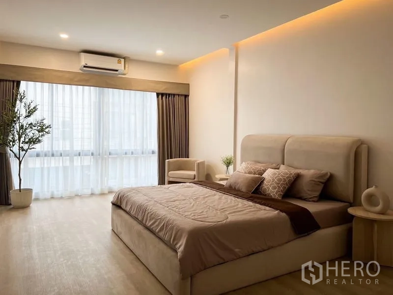 Townhouse for rent or sale - Spacious master bedroom with large windows, sheer curtains and AC in a modern Watthana townhouse.