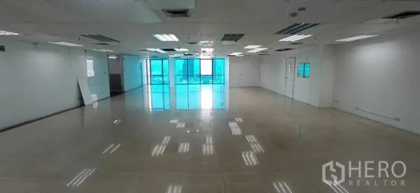Office Space for rent in Huai Khwang, Bangkok - Wide unfurnished office floor with many ceiling light panels and windows at the far end.