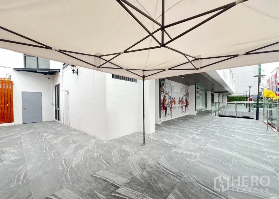 Retail Space for rent - Expansive shaded terrace area with canopy frame and open retail frontage.