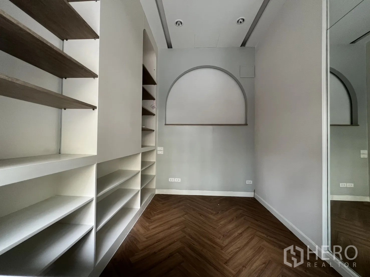 Retail Space for rent in Watthana, Bangkok - Compact retail room featuring built-in display shelves, herringbone wood flooring and an arched niche.
