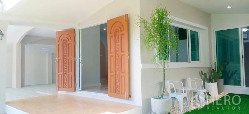 Detached House for rent in Lam Luk Ka, Pathum Thani - Front terrace with twin carved wooden doors and potted plants.