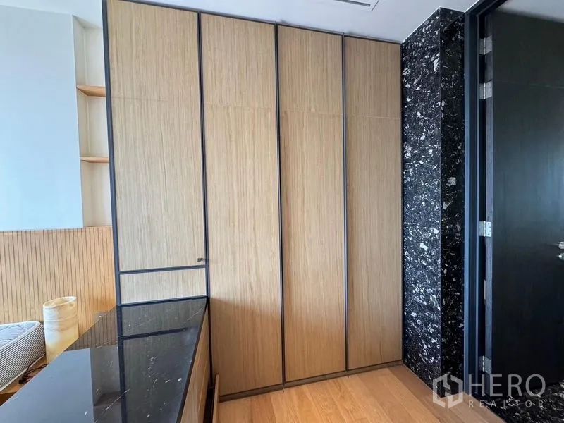 Condominium for rent - Floor-to-ceiling wooden wardrobes beside a black marble feature wall.