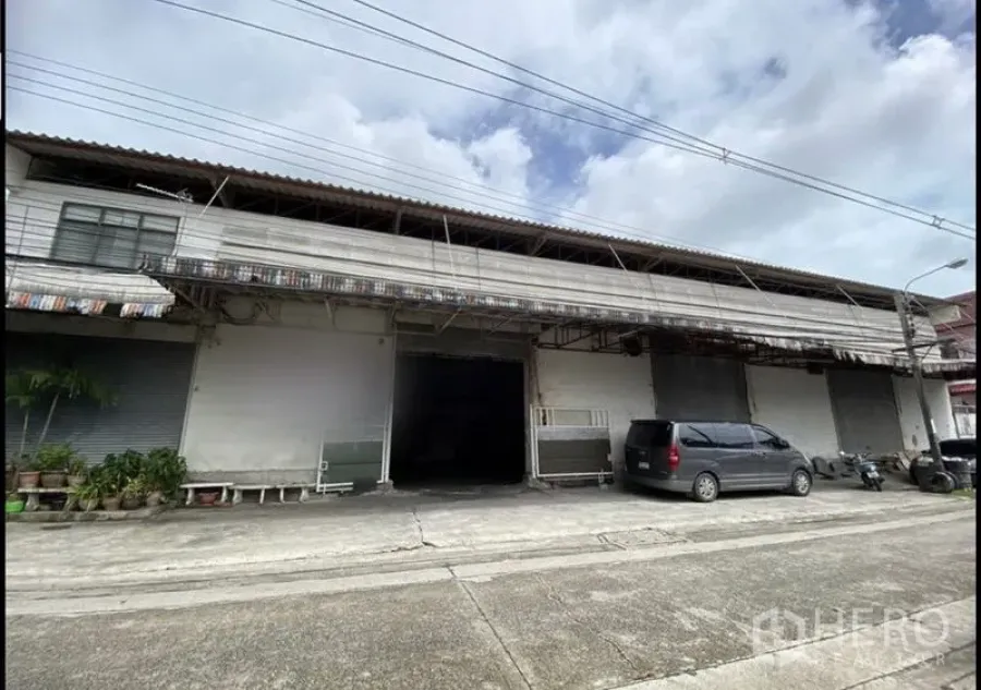 货栈 出租在Bang Khun Thian, Bangkok - Bang Khun Thian街边仓库外观，多个卷闸门，带遮棚装卸区和停车位。