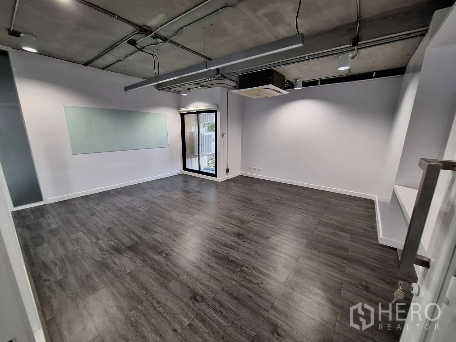 Office Space for rent - Meeting room with glass whiteboard, industrial ceiling lights and balcony access.