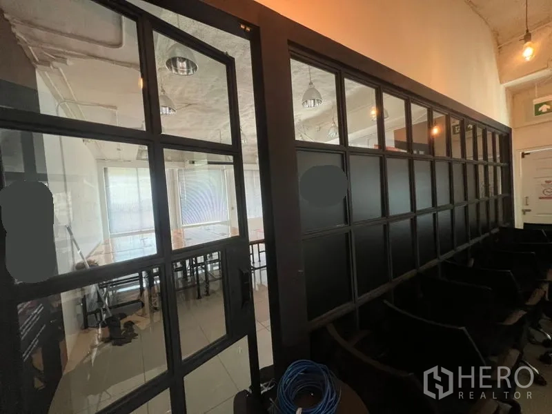 Office Space for rent in Khlong Toei, Bangkok - Corridor view of black-framed glass partitions leading to a meeting or work area.