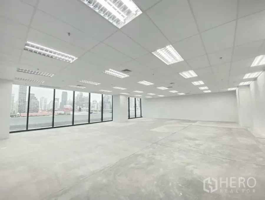 办公空间 出租在Ratchathewi, Bangkok - 明亮的开放式办公室，网格吊顶与LED灯，水泥地面，落地窗眺望曼谷天际线。