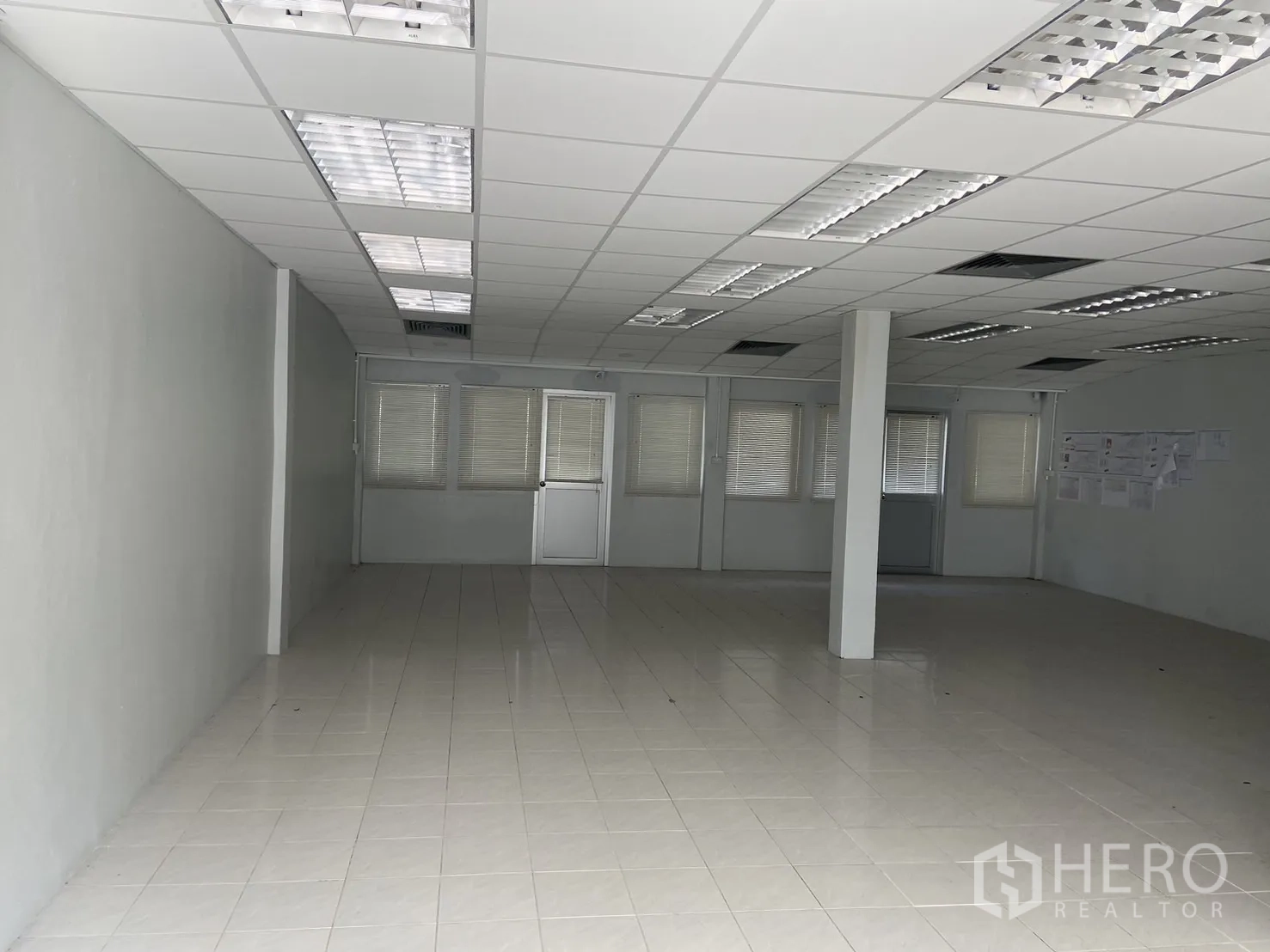 Shophouse for rent in Bang Na, Bangkok - Open office floor with grid ceiling, lighting fixtures and rows of windows.