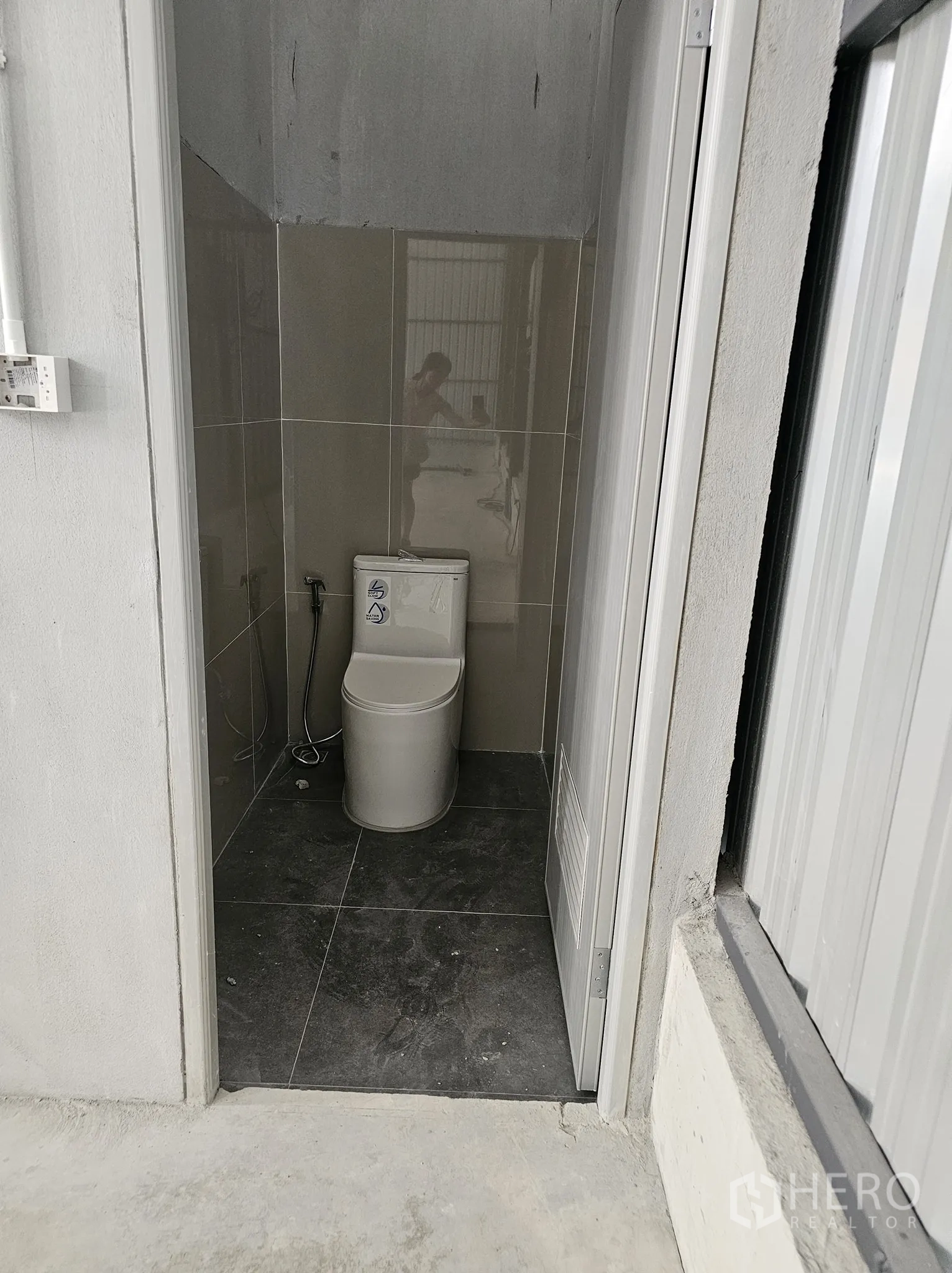 Warehouse for rent in Bang Khen, Bangkok - Interior of a restroom with a modern toilet and spray hose.