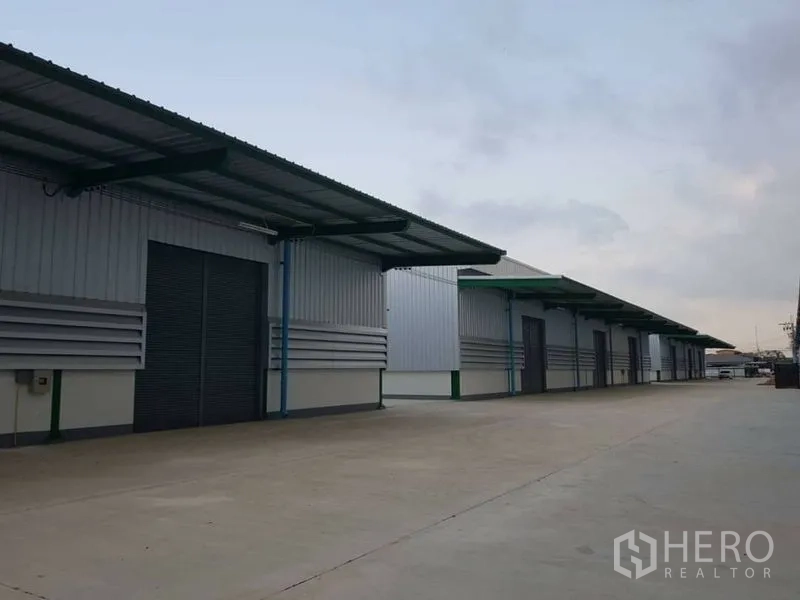 Warehouse for rent in Bang Phli, Samut Prakan - Multiple covered loading bays with roller doors along a wide maneuvering area for trucks.
