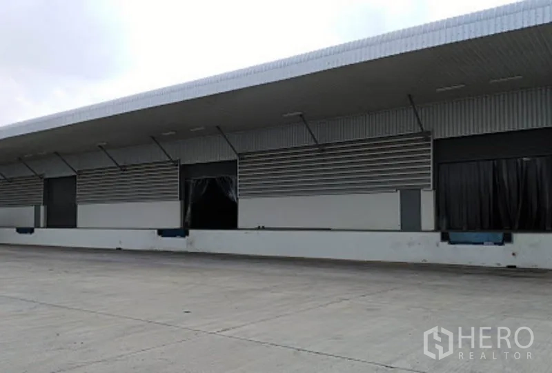 Warehouse for rent in Phra Nakhon Si Ayutthaya - Covered loading dock with multiple bays, dock levelers and a wide concrete yard at an industrial warehouse.