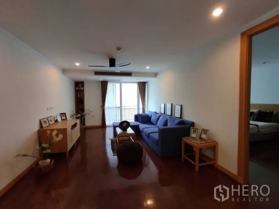 Condominium for rent in Khlong Toei, Bangkok - Family lounge with blue sofa, recessed lighting and doors to a small balcony.