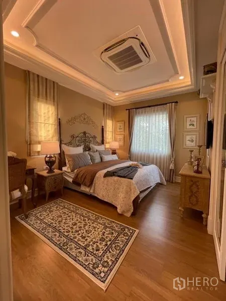 Detached House for rent or sale in Pathum Thani - Warm master bedroom with tray ceiling, wood floor and a king bed.