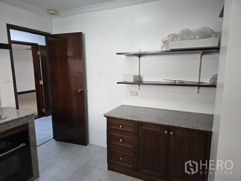Detached House for rent in Watthana, Bangkok - Kitchen corner with granite counter, wall shelves and storage cabinet.