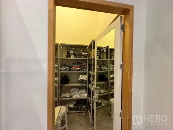 Retail Space for rent in Phra Khanong, Bangkok - Compact stock or fitting room with metal shelving and a mirrored door, organized merchandise.