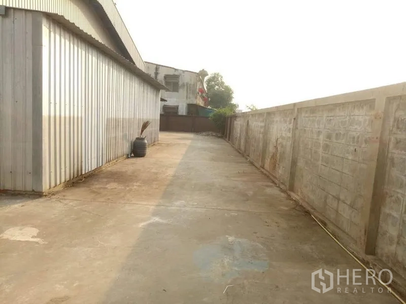 Factory for rent in Lat Lum Kaeo, Pathum Thani - Service lane beside metal-clad wall leading to the rear yard.