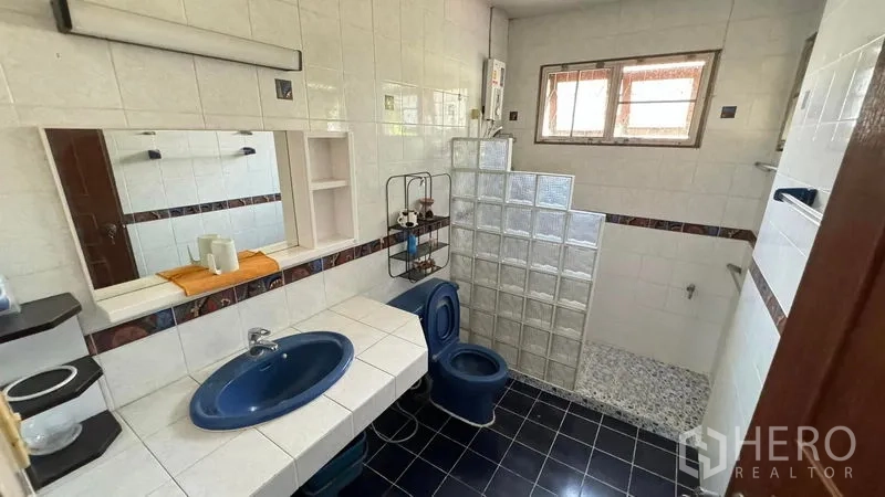 Detached House for sale in Mueang Pathum Thani, Pathum Thani - Second bathroom with blue fixtures, glass-block shower area and tiled walls.