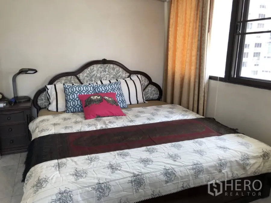 Condominium for rent in Pathum Wan, Bangkok - Primary bedroom with patterned headboard, large bed, bedside table and daylight from curtained window.