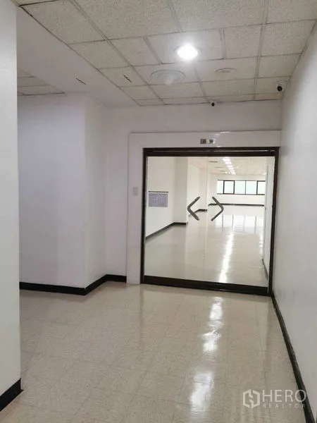 Office Space for rent in Watthana, Bangkok - Hallway leading to the office suite with double glass doors and CCTV cameras.