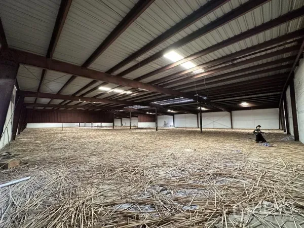 Warehouse for rent in Samut Prakan - Expansive mezzanine storage zone with metal roof structure and bright industrial lighting.
