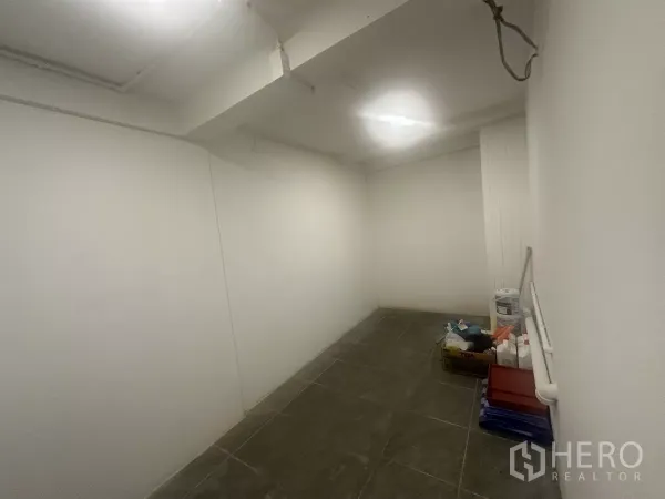 Retail Space for rent - Compact back room or storage area with dark floor tiles and supplies.