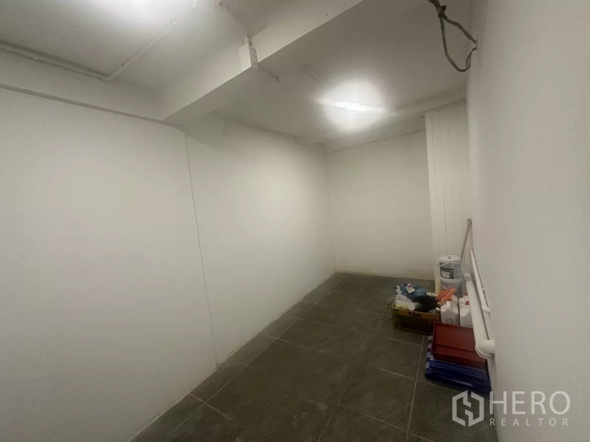 Retail Space for rent - Compact back room or storage area with dark floor tiles and supplies.