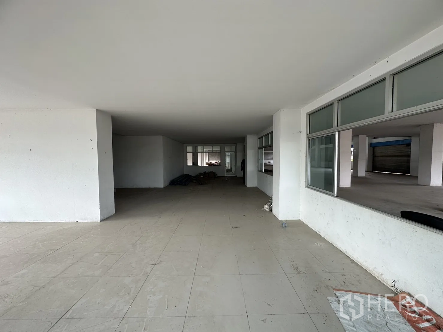 Factory for rent in Pak Kret, Nonthaburi - Long office corridor with tiled flooring and window partitions facing the yard.