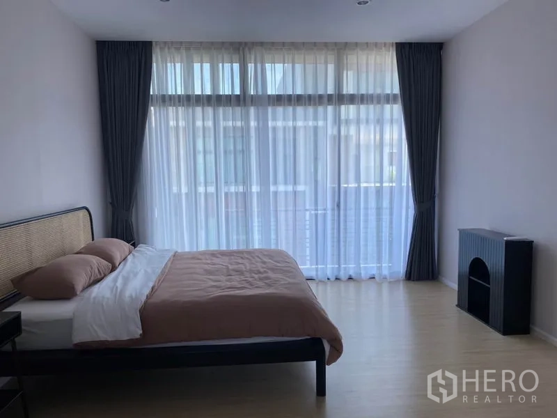 联排别墅 出租在Saphan Sung, Bangkok - 宽敞卧室，整面玻璃窗与纱帘，简约家具布置。