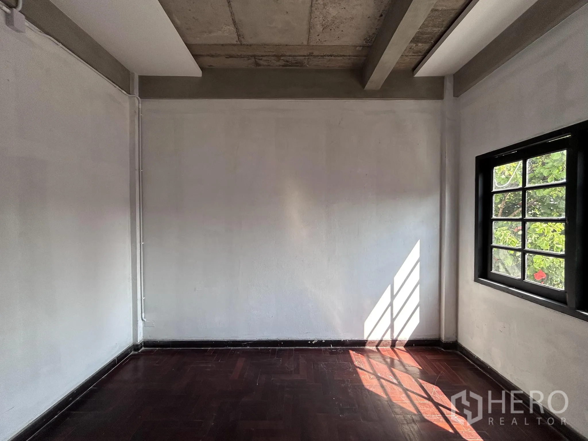 Home Office for rent or sale in Watthana, Bangkok - Cozy room with dark wood floor and leafy view through the window.
