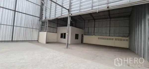 Warehouse for rent in Pak Kret, Nonthaburi - High‑ceiling warehouse interior with a small built‑in office and steel structure.