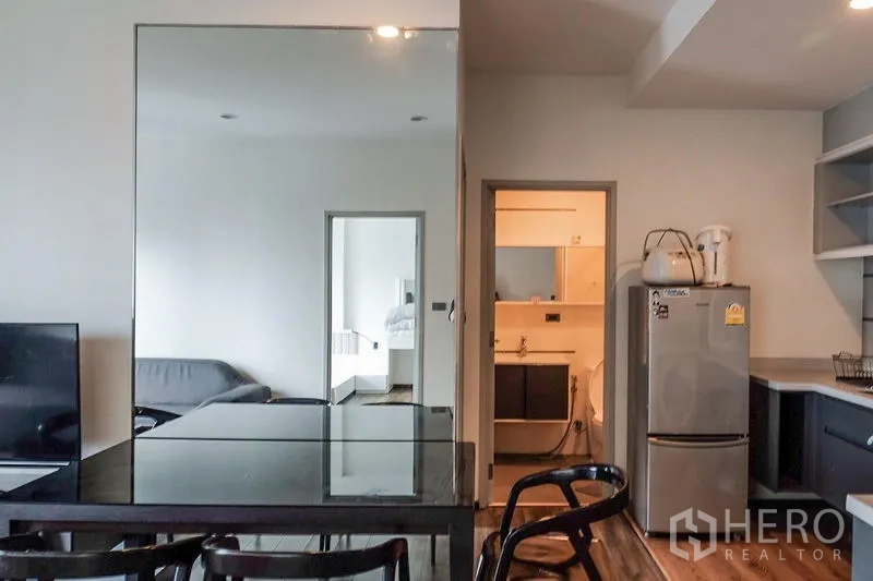 Condominium for rent in Khlong Toei, Bangkok - Alternate view of the living room showing sofa, tall window and city outlook.