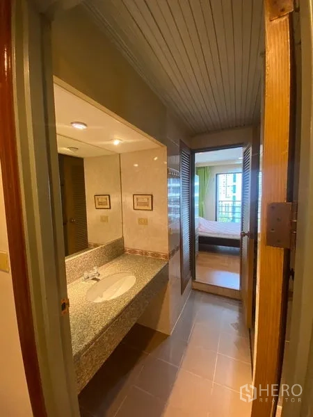 Condominium for rent in Pathum Wan, Bangkok - Bathroom with granite vanity, large mirror, tiled walls, and a doorway connecting to the bedroom.