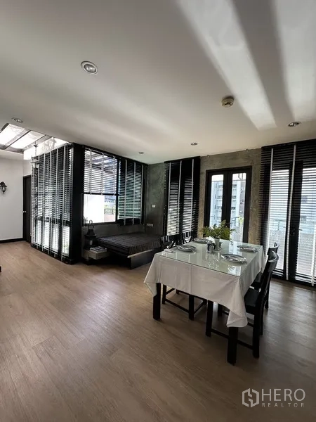 Condominium for rent in Khlong Toei, Bangkok - Dining area with large windows, blinds, and a cozy lounge daybed.