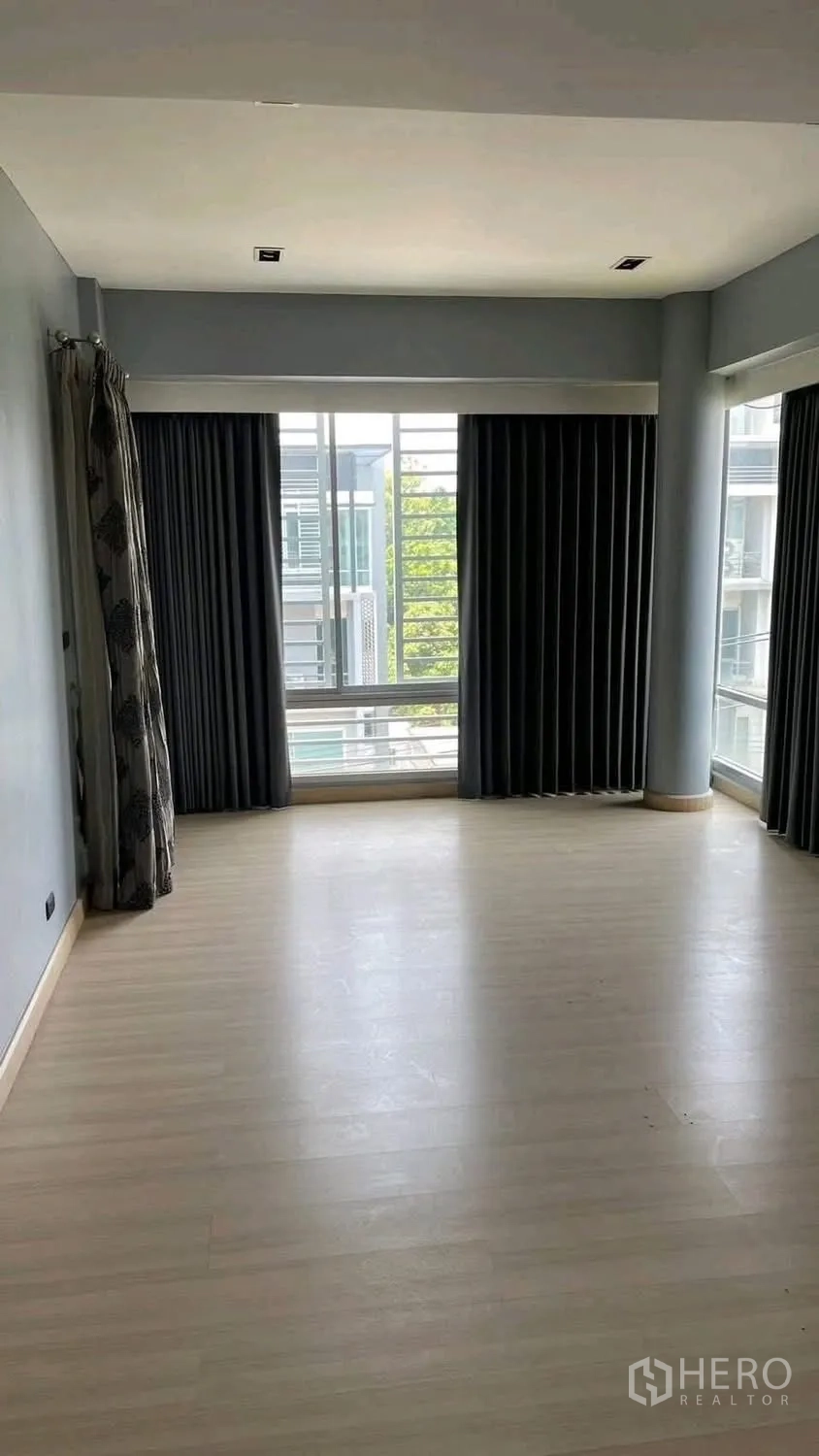 Home Office for rent or sale in Wang Thonglang, Bangkok - Empty room with light wood flooring, curtains, and corner windows.