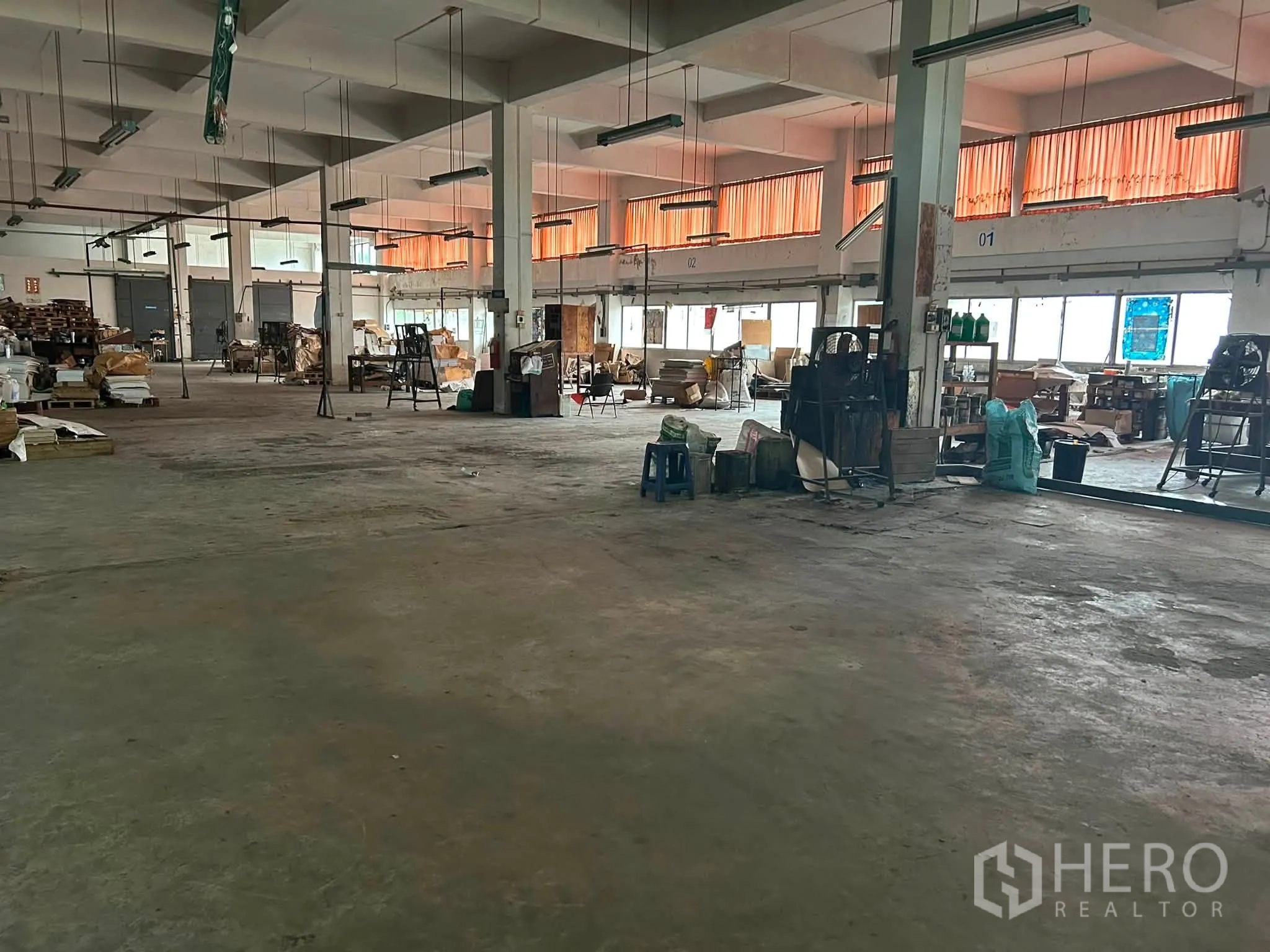 仓库 for rent in Phra Khanong, Bangkok - 开阔的仓库内部，混凝土地面、结构柱、窗户与悬吊灯具。