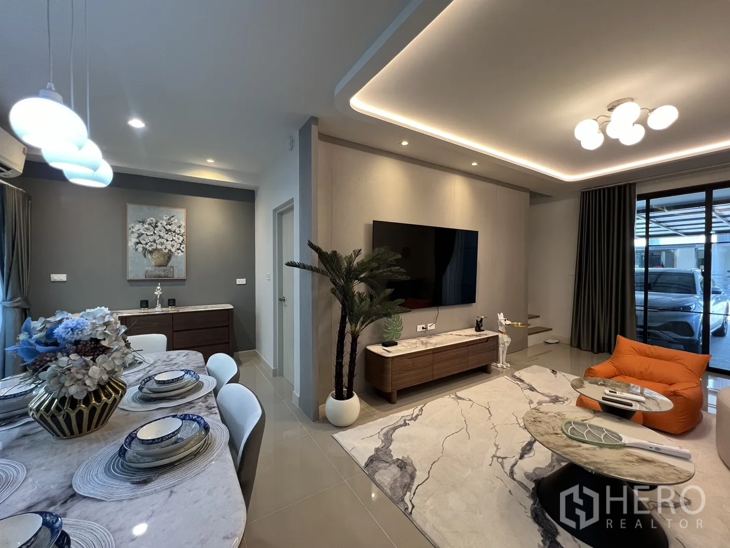 Townhouse for rent in Bang Phli, Samut Prakan - Dining area leading to a living room with wall-mounted TV and accent lighting.