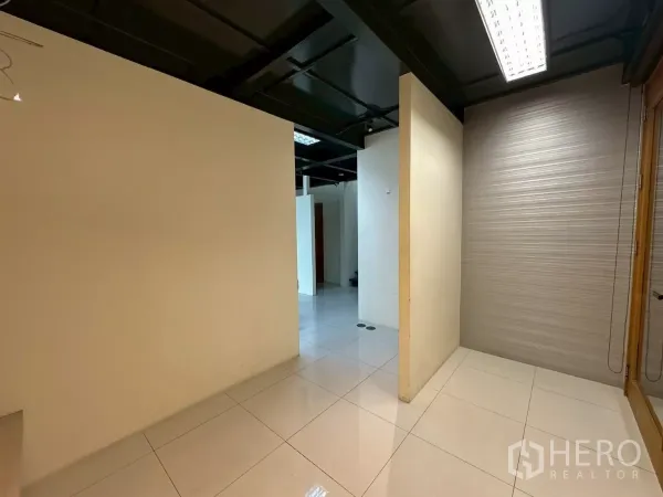 Office Space for rent in Khlong Toei, Bangkok - Entrance hallway of the duplex office with glossy white tiles and a black exposed ceiling.