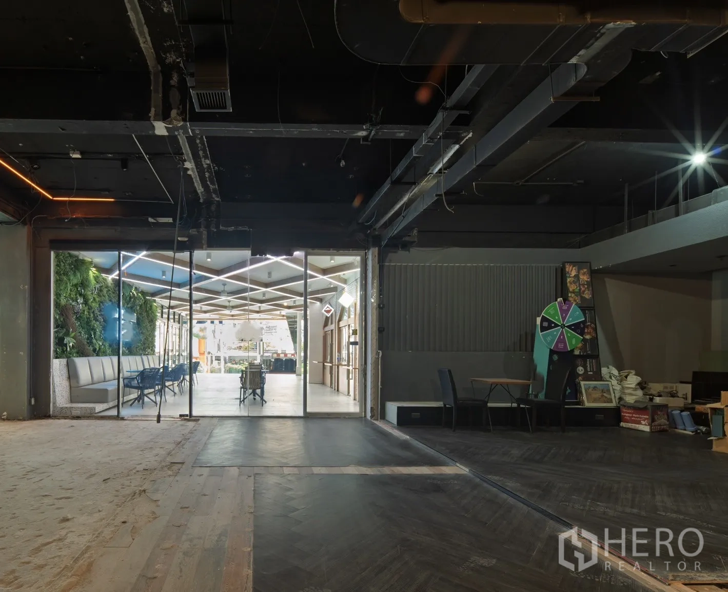 Retail Space for rent in Watthana, Bangkok - Raw retail interior with glass frontage opening to a bright atrium and green wall seating.