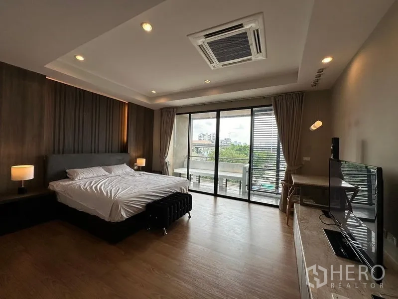 联排别墅 出租在Khlong Toei, Bangkok - 主卧带阳台、电视柜与吊顶式空调，空间宽敞。