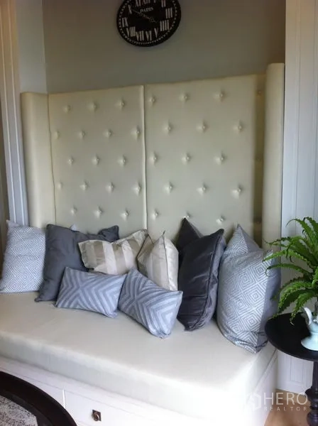 Condominium for rent in Bangkok - Cozy window seat with tufted backrest and assorted cushions next to a side table.