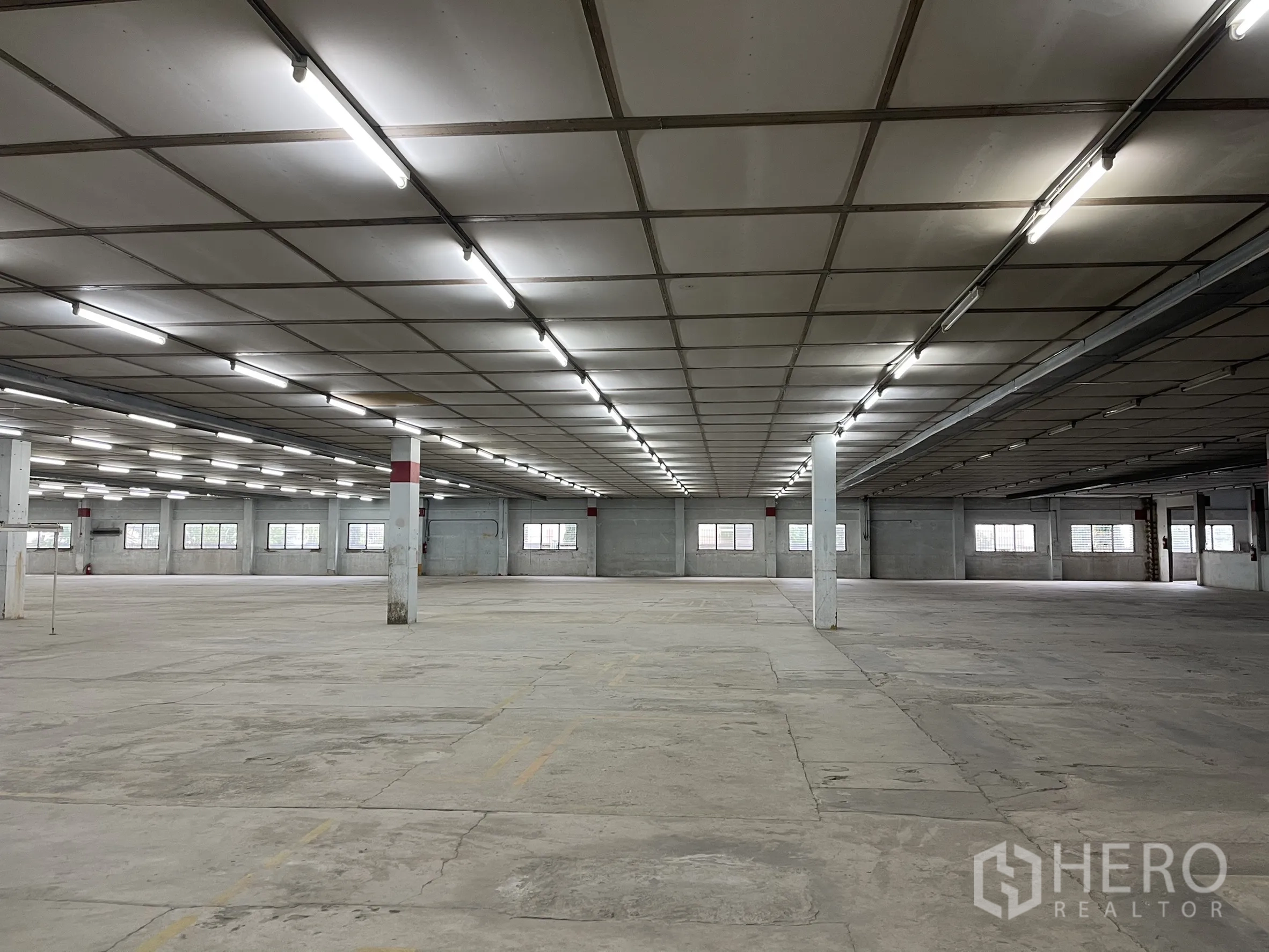 Factory for rent in Phra Samut Chedi, Samut Prakan - Large indoor industrial hall with long rows of lights, pillars and wide unobstructed space.