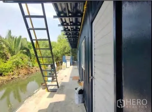 工厂 for rent or sale in Mueang Samut Sakhon, Samut Sakhon - 临近运河的人行步道与黑白色服务用房及外置楼梯。