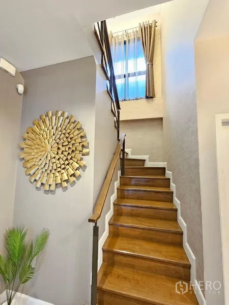 Detached House for rent in Prawet, Bangkok - Wooden staircase with tall window and modern wall art.