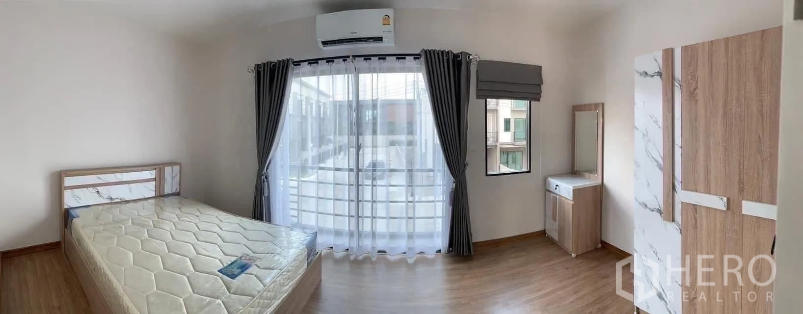 Townhouse for rent or sale in Prawet, Bangkok - Master bedroom with balcony, floor-to-ceiling curtains, wardrobe and vanity.
