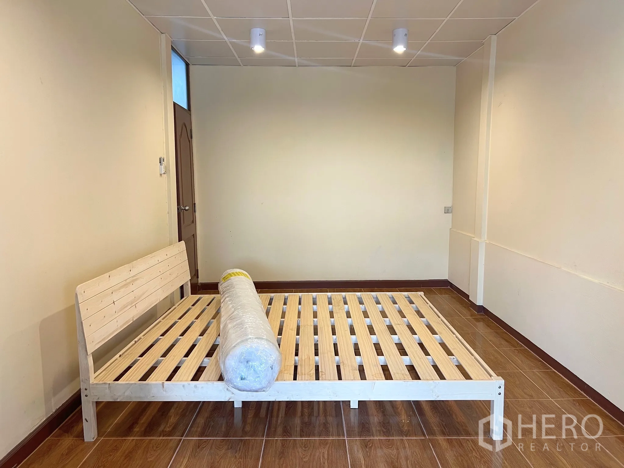 Townhouse for rent - Spacious bedroom with wood flooring and a simple wooden bed frame.