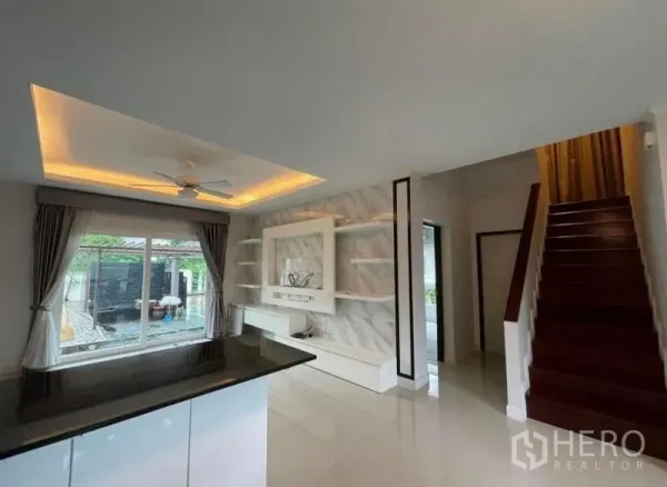 Detached House for sale in Bang Phli, Samut Prakan - View across the breakfast bar to the TV feature wall, staircase and a window toward the pool.
