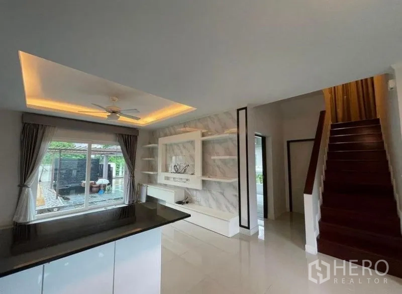 Detached House for sale in Bang Phli, Samut Prakan - View across the breakfast bar to the TV feature wall, staircase and a window toward the pool.