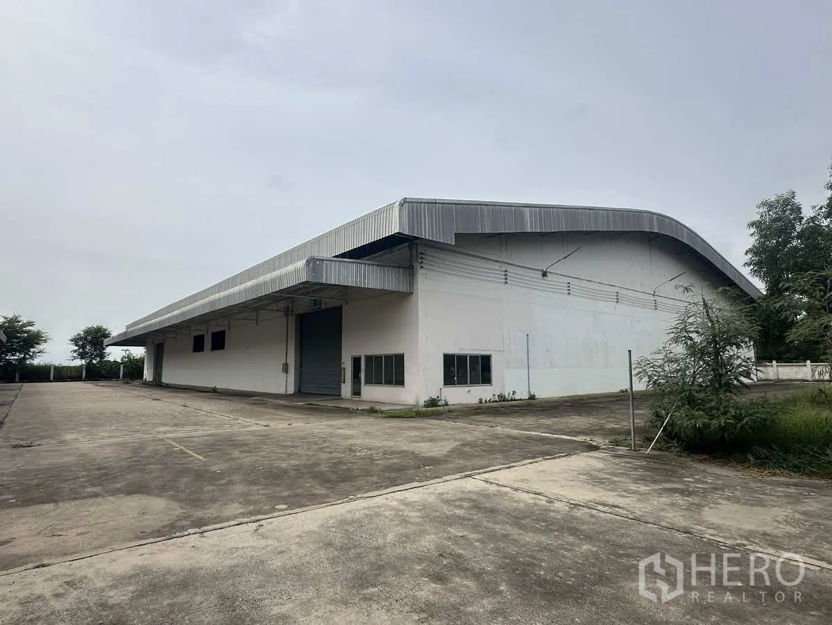 Warehouse for rent in Phra Nakhon Si Ayutthaya - Standalone warehouse exterior with curved metal roof and a wide concrete yard in Wang Noi, Ayutthaya.