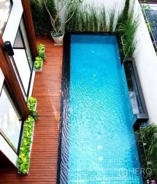 บ้าน ให้เช่าในKhlong Toei, Bangkok - ภาพมุมสูงของสระแนวยาว พร้อมพื้นไม้และต้นไม้ตกแต่งข้างผนังขาว